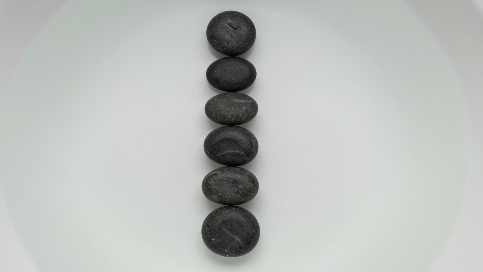 Stacked Smooth Black Stones on a Minimal White Surface