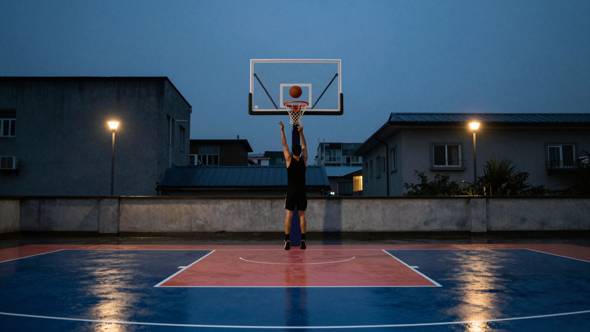 Basketball Player Shooting at Dusk on a Rainy Outdoor Court